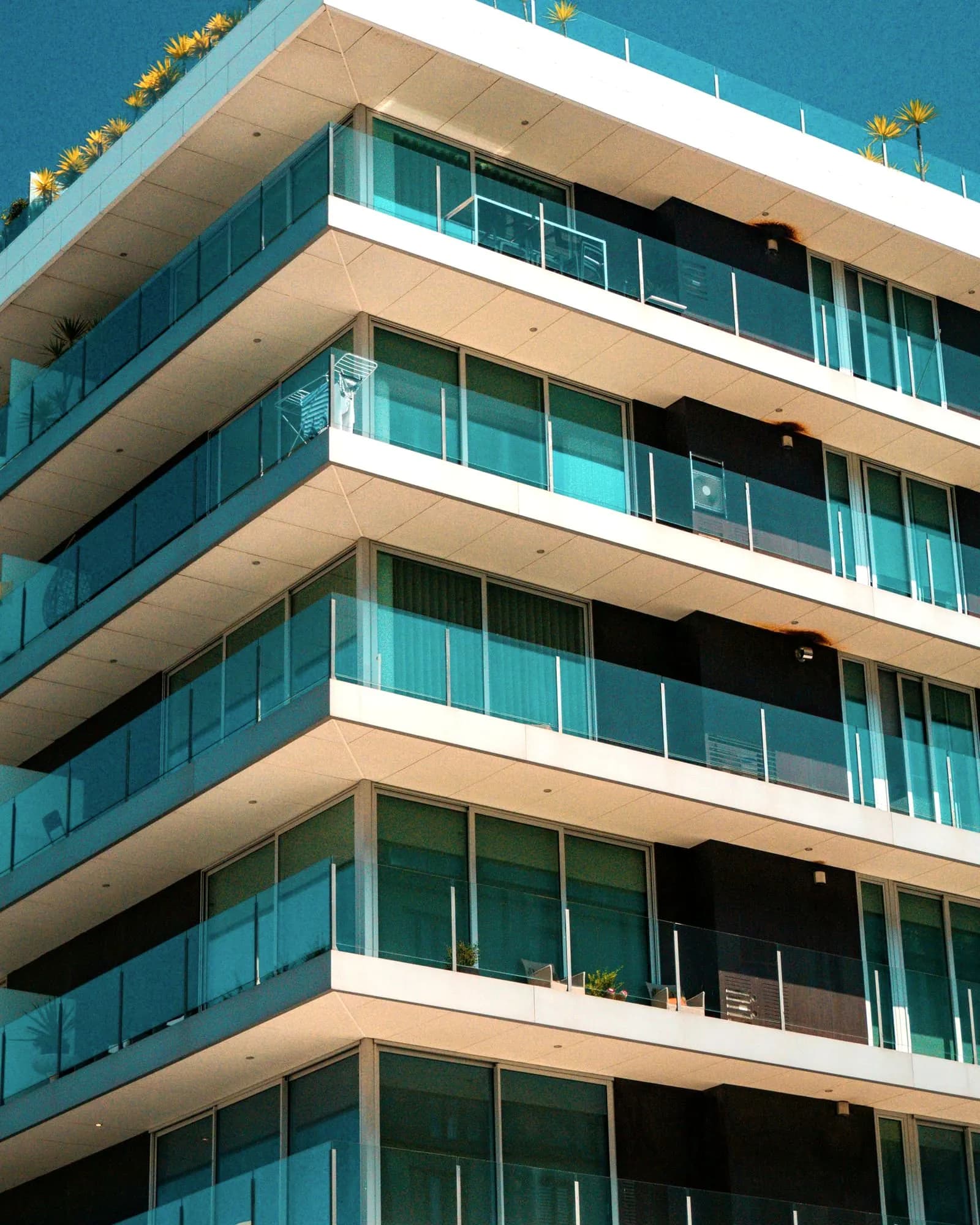 An apartment building with glass balconies and plants